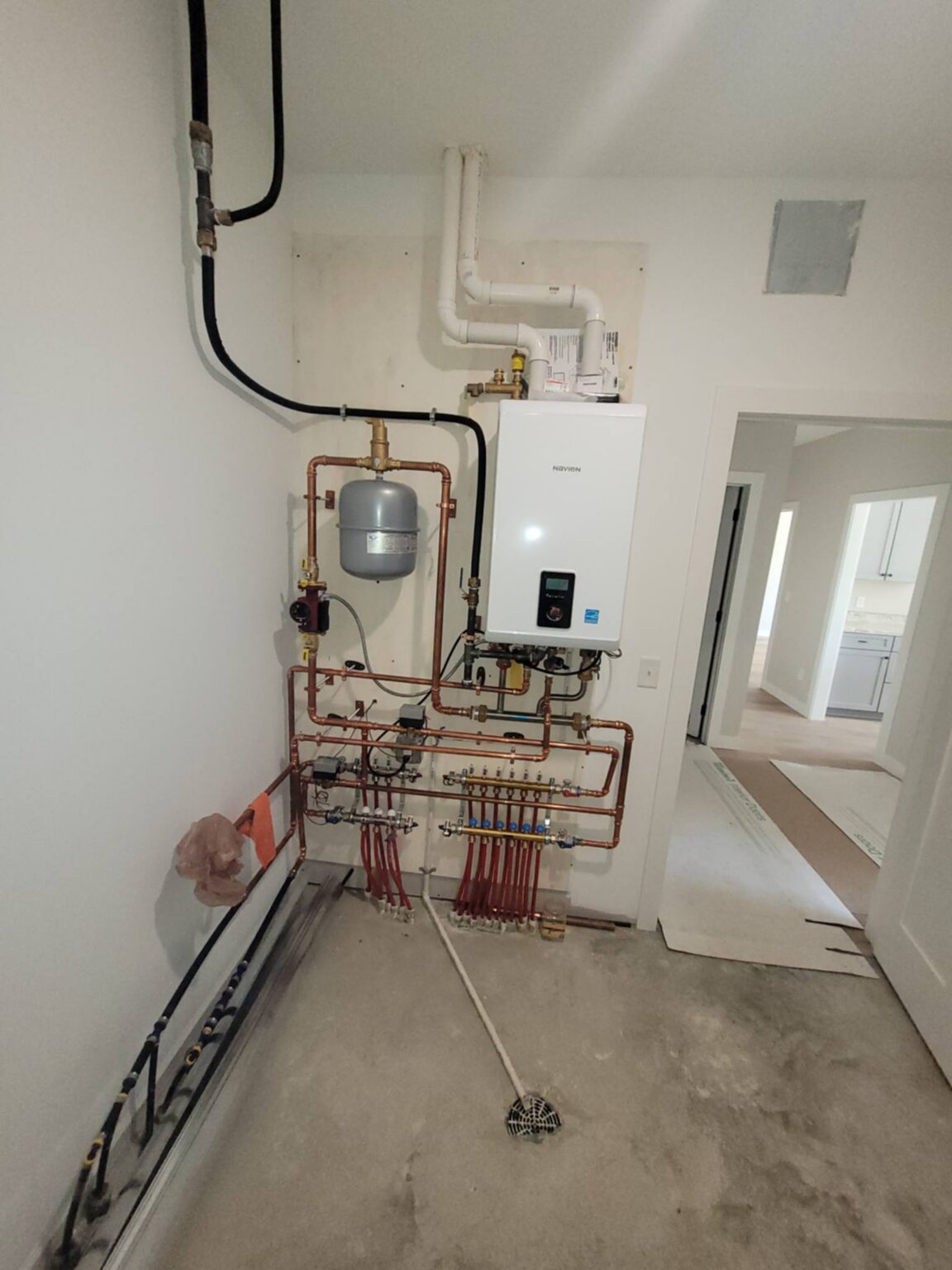 Indoor HVAC system with exposed pipes, electrical components, and a wall-mounted control unit.