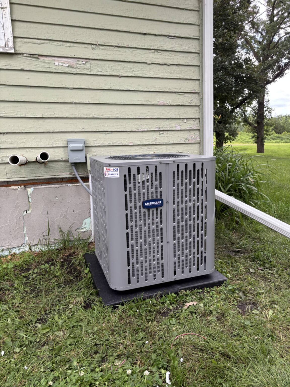 Outdoor American Standard HVAC unit installed on a concrete pad beside a residential building.